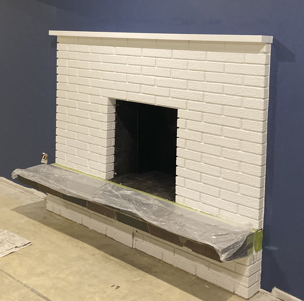 White painted brick fireplace on a blue wall