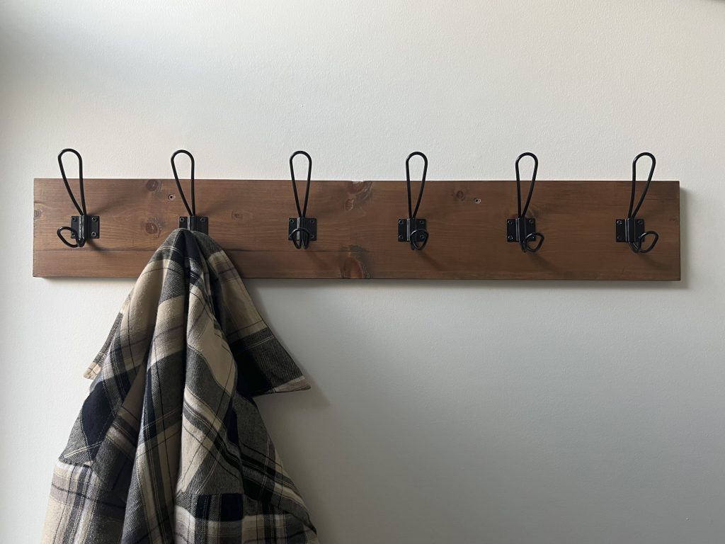 Wood coat rack installed with plaid jacket hanging on it